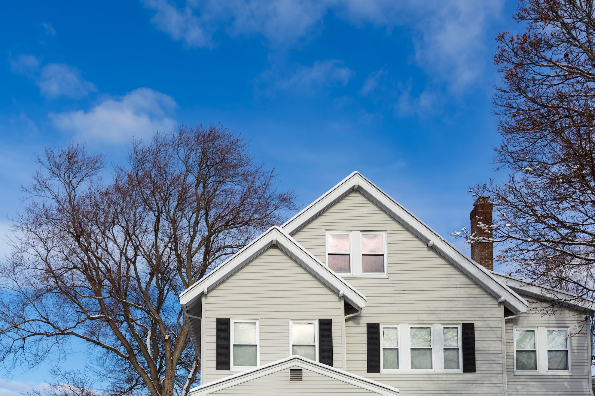 Classic gabled house with bare trees on a winter day